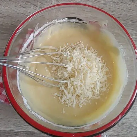 Ayak tepung jadi satu dengan baking powder, baking soda, garam dan vanili lalu masukkan ke dalam adonan secara bertahap. Terakhir masukkan keju parut, aduk sampai semua bahan tercampur dengan rata.