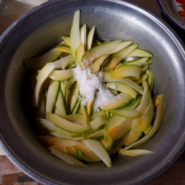 Kupas mangga dan potong tipis - tipis. Campurkan mangga dengan garam, aduk rata dan diamkan selama 1 jam. Remas - remas dan cuci hingga bersih (3 kali cuci).