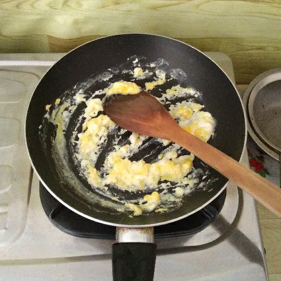 Orak-arik telur lalu sisihkan di tepi wajan anti lengket.