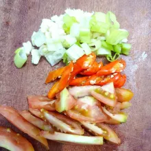 Cincang bawang putih, daun bawang, dan tomat.