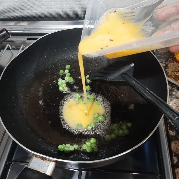 Tumis kacang polong hingga setengah matang, lalu masukkan kocokan telur, dan orek hingga telur matang.