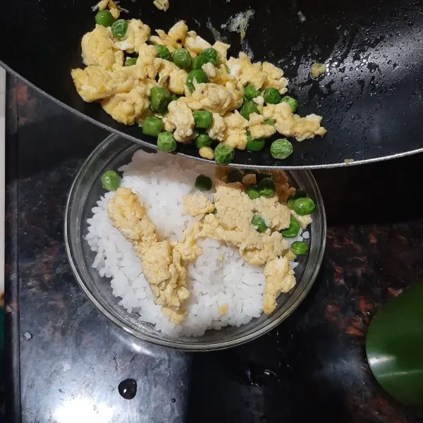 Masukkan nasi hangat ke mangkok saji, lalu masukkan orek telur dan kacang polong.