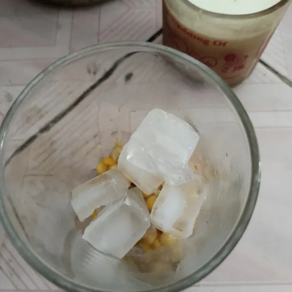 Masukkan jagung manis pipil ke dalam gelas dan tambahkan es batu.