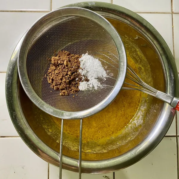 Tambahkan cokelat bubuk, baking powder dan soda kue. Ayak lalu aduk rata.