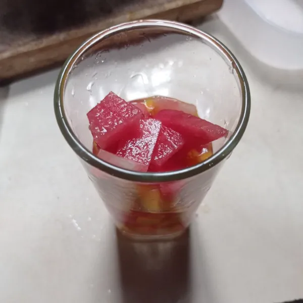 Masukkan es batu, mangga, dan semangka ke dalam gelas saji