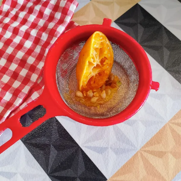 Peras air jeruk manis sambil di saring untuk menjadi jus jeruk.
