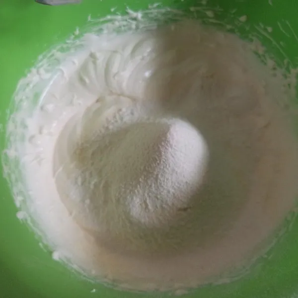 Selanjutnya masukkan campuran tepung terigu, susu bubuk, baking powder, dan vanili sambil diayak. Mixer sebentar dengan kecepatan rendah hingga rata.