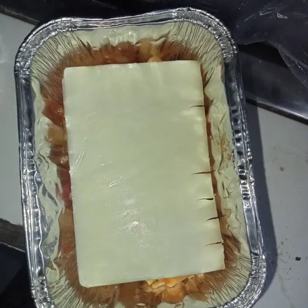 Masukkan dua sendok makan macaroni ke dalam aluminium cup, lalu tambahkan keju slices