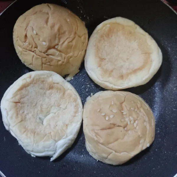 Belah 2 roti bun kemudian oles margarin salah satu sisinya, panggang hingga kecoklatan.
