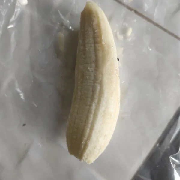Buka pisang lalu letakkan diatas plastik bening.