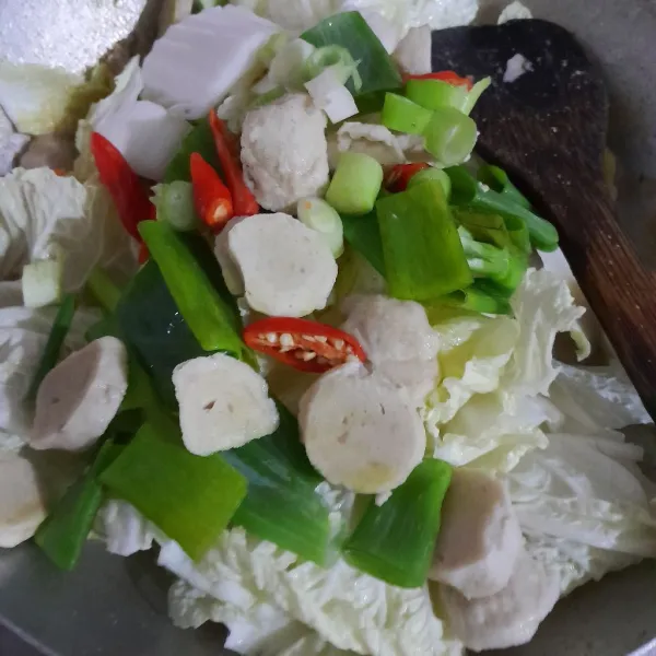 Masukkan juga daun bawang, irisan cabe rawit merah dan bakso ayam, aduk rata dan masak hingga sawi setengah matang. Sajikan!