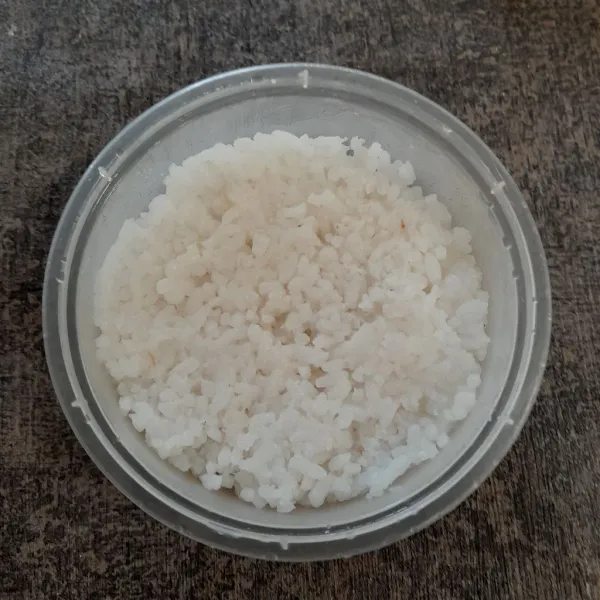 Ambil satu centong nasi, masukkan ke dalam mangkok plastik lalu tekan.