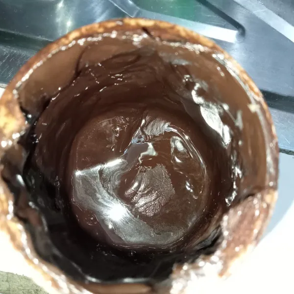 Siapkan cokelat glaze, turunkan sisa cokelat glaze yang terdapat pada pinggiran toplesnya