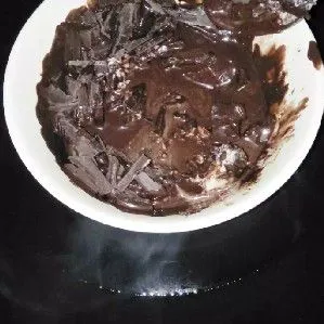 Taruh coklat dan mentega putih di mangkok tahan panas. Panaskan air di wajan, tunggu mendidih lalu matikan. Setelah itu langsung taruh mangkok dalam wajan saat masih panas lalu aduk coklat hingga leleh (coklat di tim).