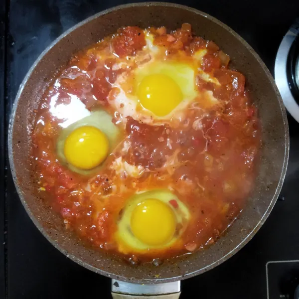 Buat lubang dengan sendok, kemudian tambahkan telur ke dalamnya. Bubuhkan garam dan lada di atas telur, tutup fry pan. Masak selama 7-10 menit hingga telur set.