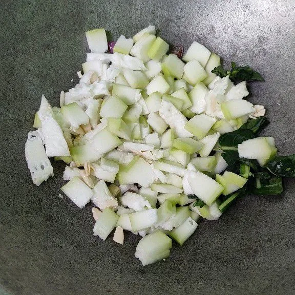Masukkan labu dan sebagian daun brokoli. Tambahkan sedikit air dan masak hingga setengah matang.