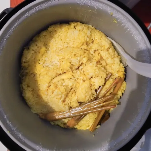 Jika sudah kembali ke mode "warm", aduk rata lagi dan nasi kuning siap untuk disajikan.