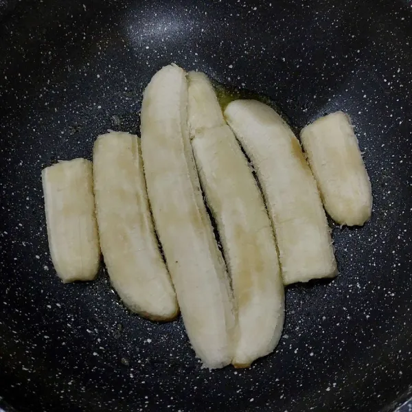 Lelehkan margarine di wajan, taburi gula pasir, lalu belah pisang dan susun di dasar wajan.