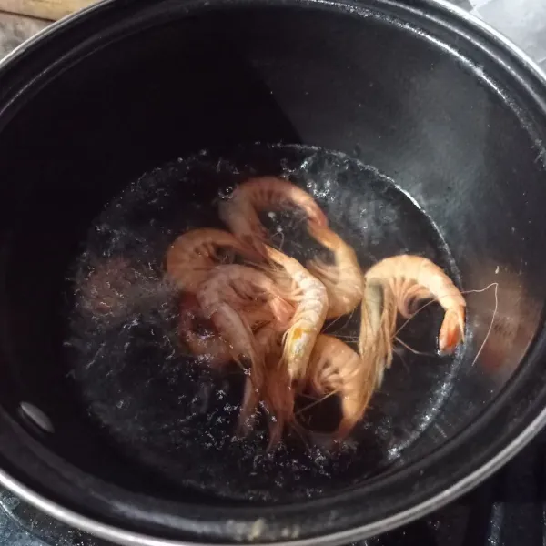 Rebus air sampai mendidih lalu masukkan udang, masak setengah matang.