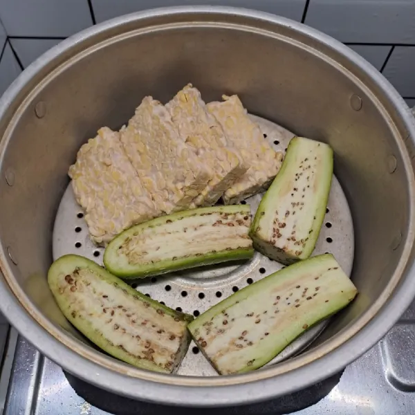 Potong tempe dan terong sesuai selera. Panaskan kukusan sampai air mendidih, kukus tempe dan terong sampai matang. Angkat dan sisihkan.