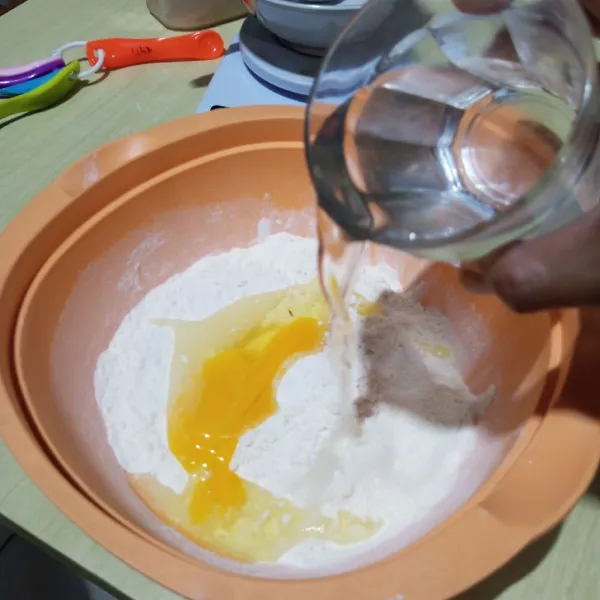 Tambahkan telur, kuning telur, dan susu cair. Aduk rata, masukkan air dingin sedikit-sedikit sambil diuleni sampai kalis.