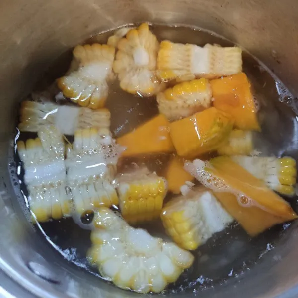 Didihkan air, masukkan labu kuning dan jagung manis, masak hingga setengah matang.