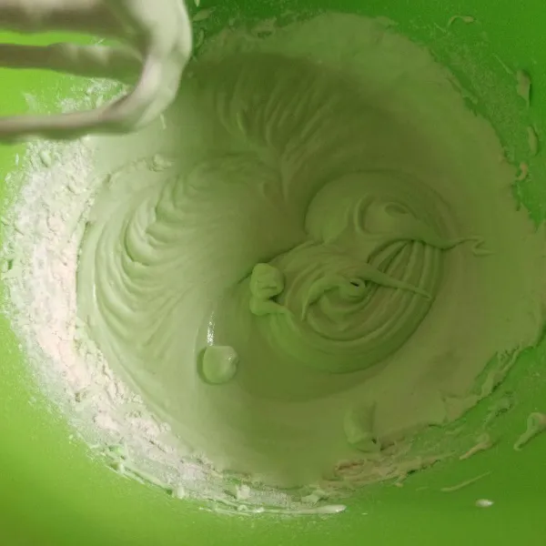 Selanjutnya masukkan tepung terigu, pasta pandan, garam, dan santan secara bertahap. Mixer dengan kecepatan rendah hingga tercampur rata.