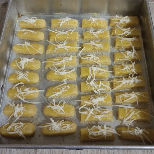 Tata di loyang yang disemir margarin tipis, oles dengan kuning telur dan keju parut. Oven sampai matang