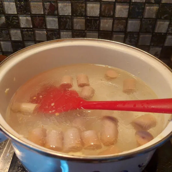 Dalam panci tumis bawang putih setekah layu masukan sosis nya goreng sampai wangi lalu beri air biarkan mendidih