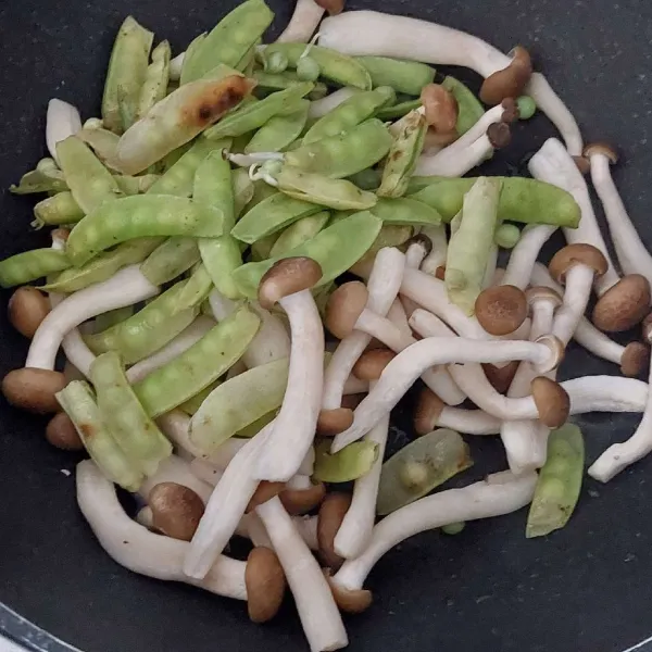 Tambahkan jamur shimeji dan kacang ercis, lalu tumis hingga layu