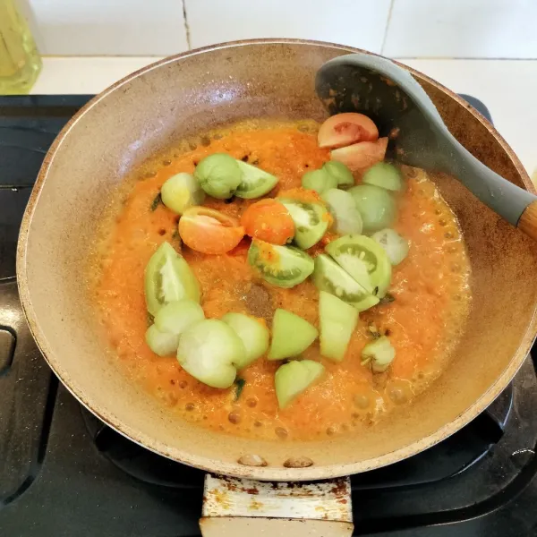 Masukkan daun jeruk, salam, lengkuas, serta potongan tomat dan belimbing wuluh