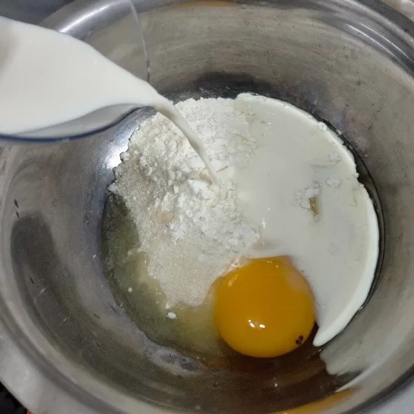 Masukkan tepung terigu, gula pasir, dan garam ke dalam wadah, lalu tambahkan telur dan susu cair, aduk hingga rata
