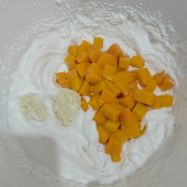 Mixer wipping cream dan air es hingga kaku, lalu masukkan potongan mangga