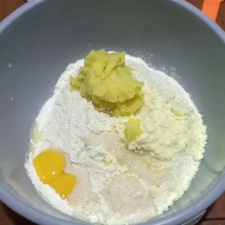 Di wadah campur terigu, gula pasir, susu bubuk, ragi, kuning telur, dan kentang tuang air secara bertahap uleni sampai setengah kalis.