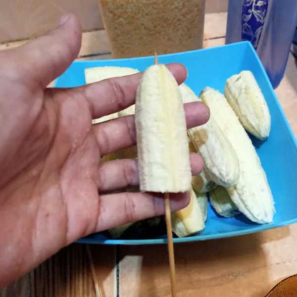 Kupas kulit pisang dan bagi 2 lalu tusuk dengan lidi.