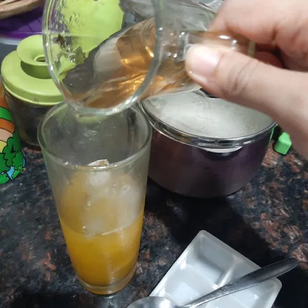 Tuang teh chrysanthemum ke dalam gelas yang telah berisi es jeruk peras.