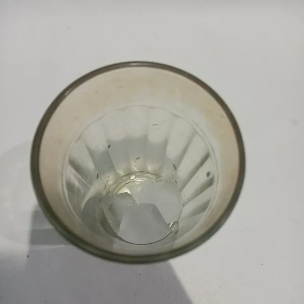 Tuangkan es batu pada gelas saji.