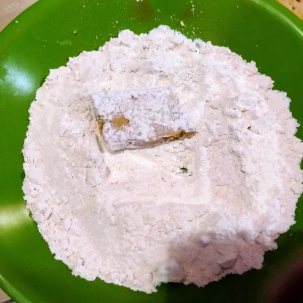 Gulingkan potongan nugget ke tepung terigu.