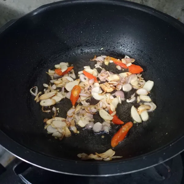 Tumis irisan bawang dan cabai rawit sampai layu.