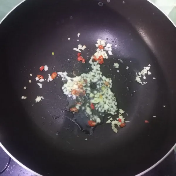 Panaskan minyak, tumis bawang putih dan cabai rawit.
