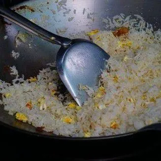 Masukkan nasi putih ke dalam wajan. Aduk rata dengan telur dan daging.