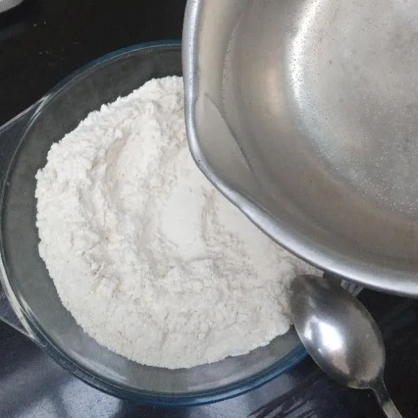 Masukkan tepung ke dalam mangkuk, lalu siram dengan air panas, aduk rata.