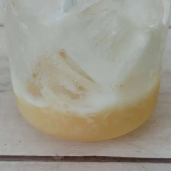 Tuang kental manis ke gelas berisi air.