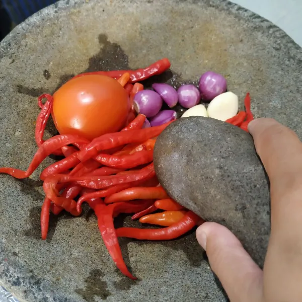Haluskan cabe merah keriting, cabe rawit, tomat, bawang merah, bawang putih dan terasi menggunakan cobek.