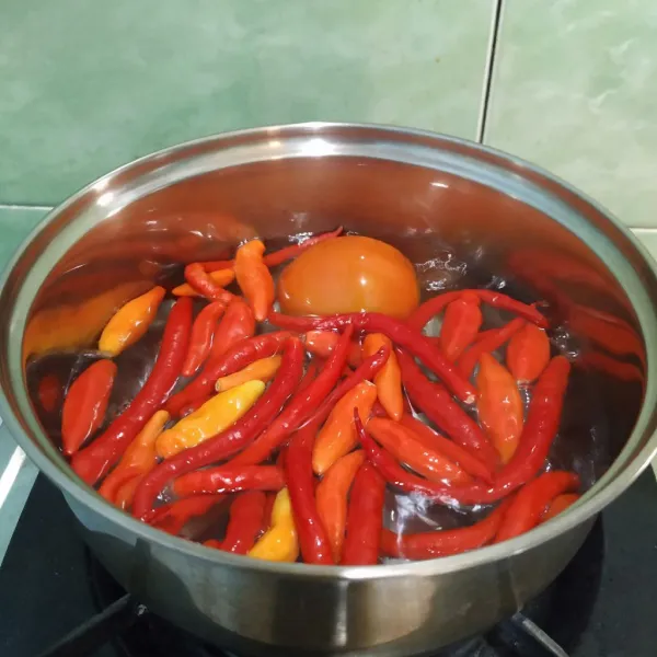 Masukkan cabe merah keriting, cabe rawit merah dan tomat ke dalam panci, rebus selama 15 menit menggunakan api sedang. Angkat dan tiriskan.
