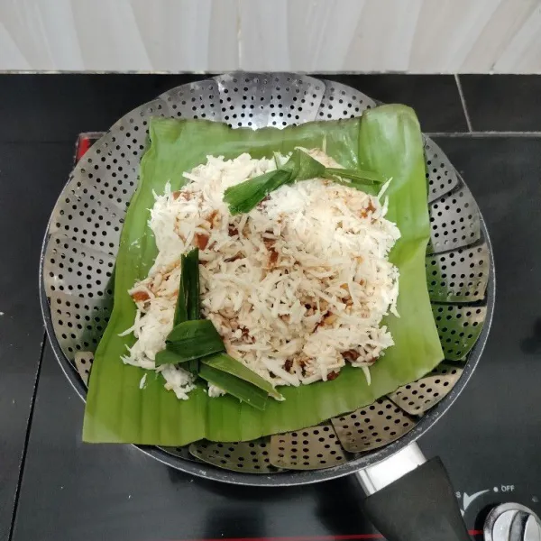 Masukkan adonan ke dalam kukusan yang sudah di alasi daun pisang. Tambahkan daun pandan di atasnya.