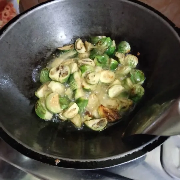 Panaskan minyak, kemudian goreng terong hijau bulat hingga layu, lalu angkat dan tiriskan.