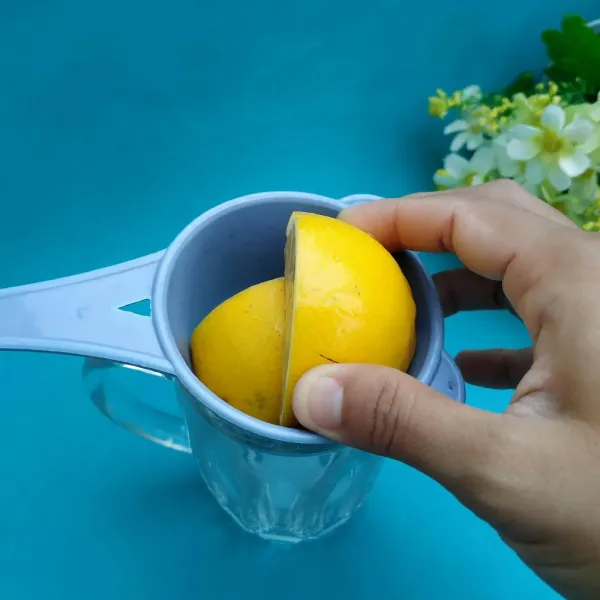 Siapkan gelas dan saringan, lalu peras lemon.