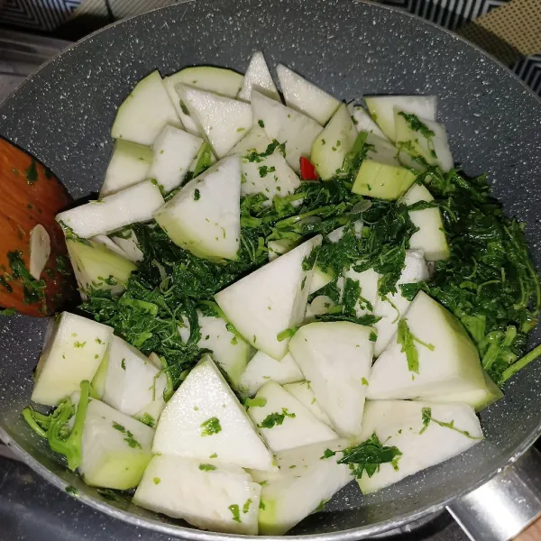 Masukkan labu air dan aduk-aduk sampai layu, lalu tuang air dan masak sampai matang.