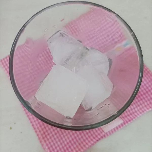 Dalam gelas saji masukkan es batu.